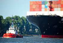 id514372 Containerschiff vor Hamburg-Finkenwerder mit Schlepper und Moeven